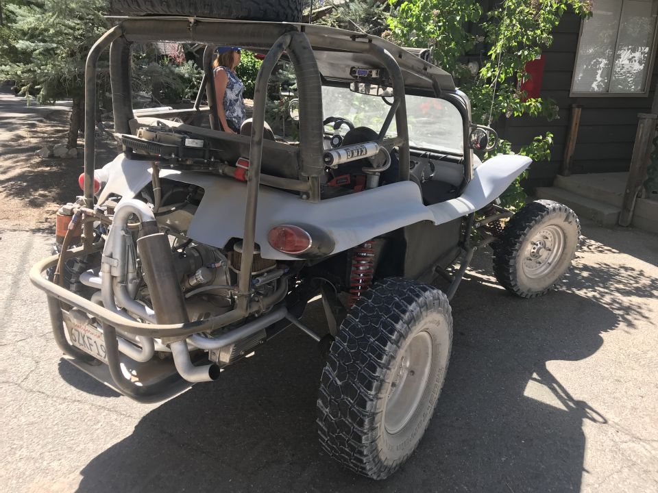 Rear 3/4 view of a custom dune buggy with roll cage and exposed engine.