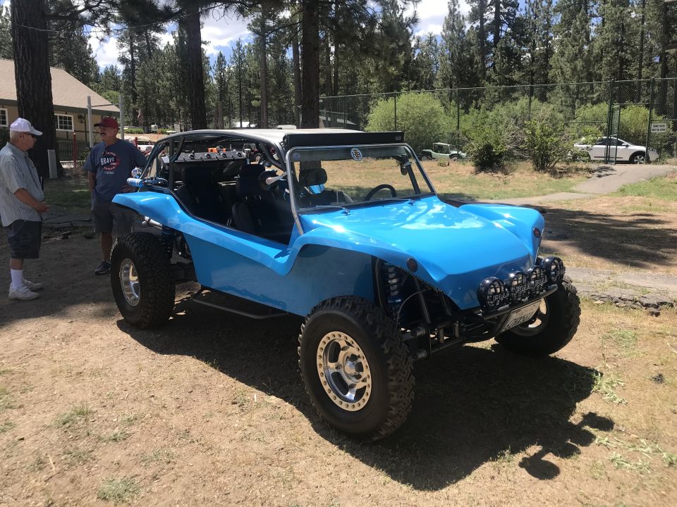 Blue custom dune buggy with off-road tires and spotlights.