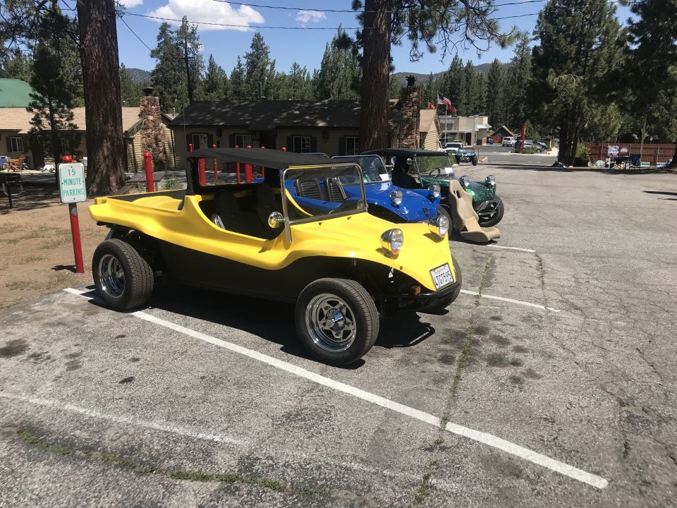Yellow and black dune buggy parked in a lot with other buggies.