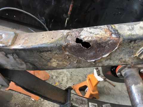 1992 Jeep Wrangler - A close-up view shows significant rust and a hole in the metal frame of a vehicle, likely a Jeep Wrangler. The frame is supported by jack s…