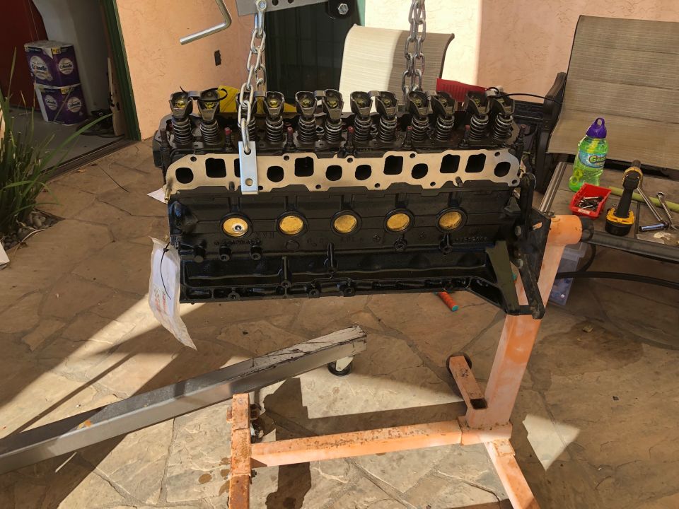 Black V8 engine block on an orange engine stand, suspended by chains.