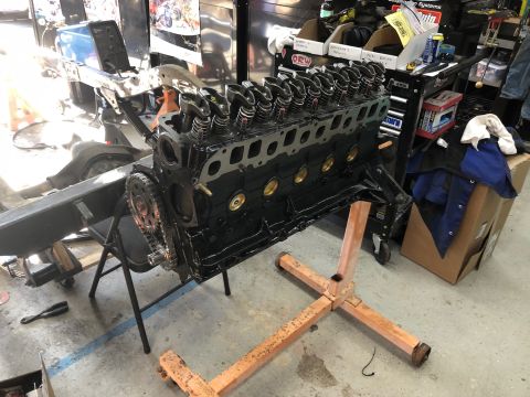 1992 Jeep Wrangler - A black V8 engine block is mounted on an orange engine stand in a garage. The engine appears to be partially assembled with valve covers an…