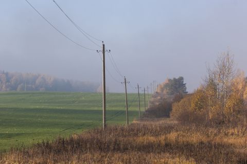 1993 Ford Bronco - A rural landscape with telephone poles lining a dirt road next to a green field and autumn trees.