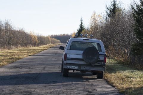 1993 Ford Bronco - The rear view of a silver Ford Bronco is parked on the side of a paved rural road. The vehicle has a spare tire mounted on the back and fou…