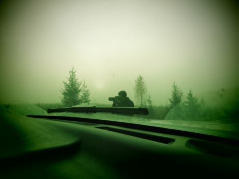 1993 Ford Bronco - View from inside a vehicle looking out at a person holding a camera in a foggy, wooded landscape. The dashboard and windshield wipers are v…