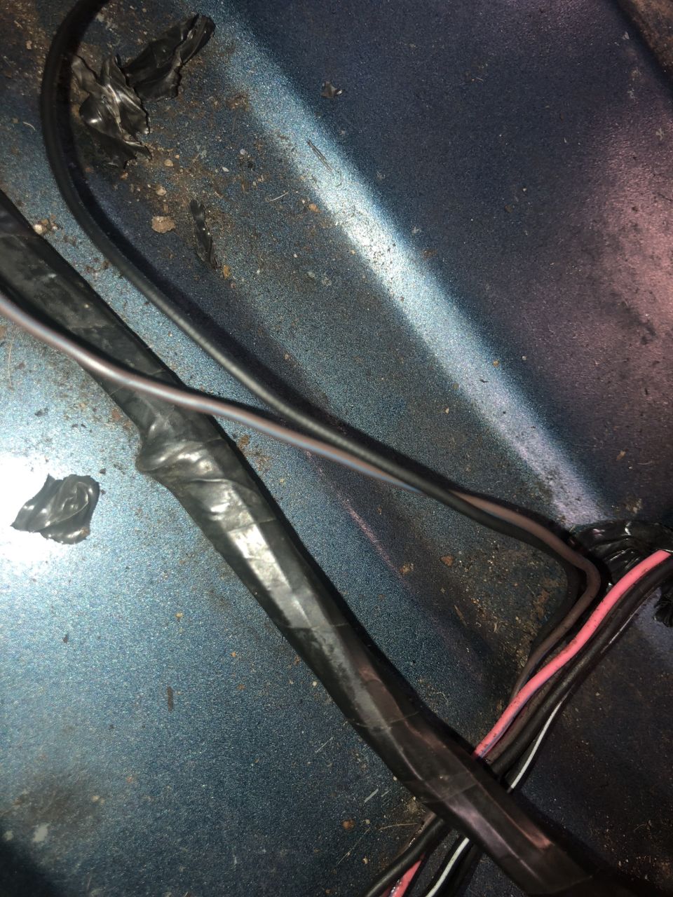 Close-up of taped wires on a blue metallic surface.
