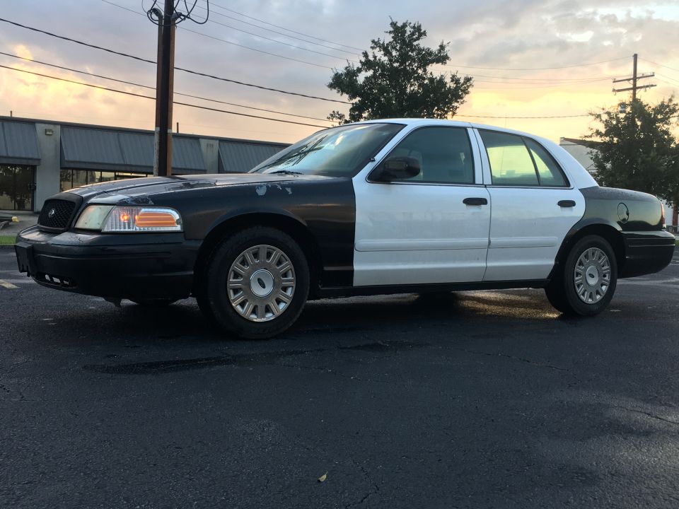 Side view of a black and white Ford Crown Victoria sedan.