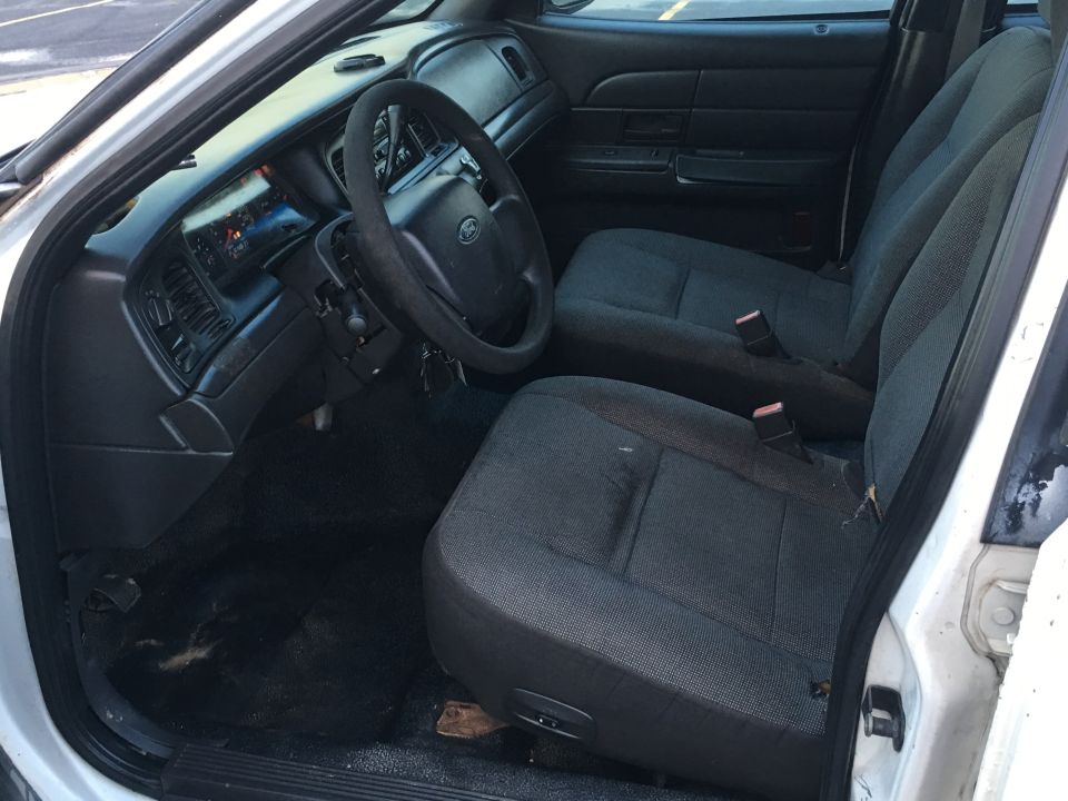 Interior of a white Ford Crown Victoria showing seats, dashboard, and steering wheel.
