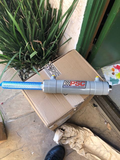 1992 Jeep Wrangler - A new PSC Performance Steering Components power steering cylinder is shown resting on a cardboard box. The cylinder has a grey body with a…