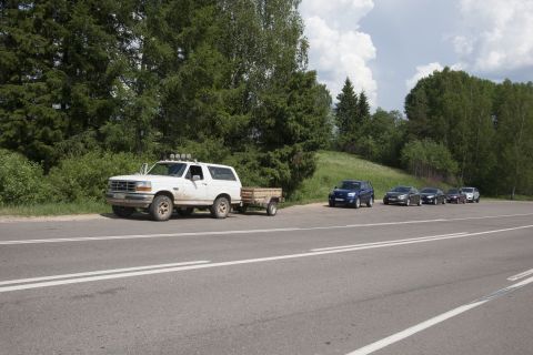1993 Ford Bronco - A white Ford Bronco with a trailer is parked on the side of a road next to a line of other cars. The Bronco has four auxiliary lights mount…