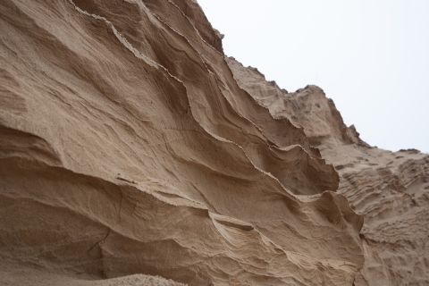 1993 Ford Bronco - A close-up, low-angle view of layered sand formations with a bright, overcast sky in the background.