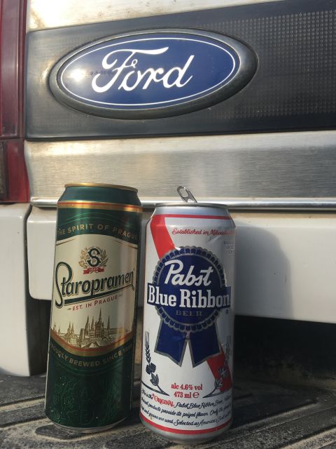 1993 Ford Bronco - Two beer cans, a Staropramen and a Pabst Blue Ribbon, are placed in front of the Ford emblem on the tailgate of a vehicle.