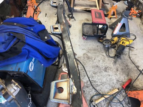 1992 Jeep Wrangler - A collection of tools and welding equipment is laid out on a concrete floor, including a blue welding jacket, a Miller welding machine, ang…