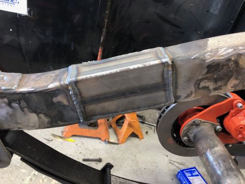 1992 Jeep Wrangler - A close-up view of a welded metal frame section, likely part of a vehicle's chassis, supported by orange jack stands. Visible components in…