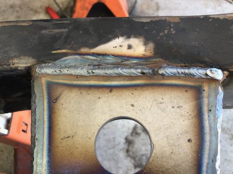 1992 Jeep Wrangler - A close-up view of a freshly welded joint on a vehicle's frame, showing the iridescent heat discoloration and the texture of the weld bead.…