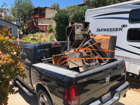 1992 Jeep Wrangler - A black Ram pickup truck is parked next to a white recreational vehicle, with the truck bed loaded with scrap metal parts secured by orange…