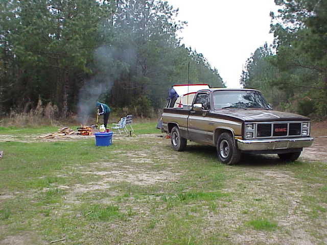Brown two-tone GMC pickup truck parked at wooded campsite