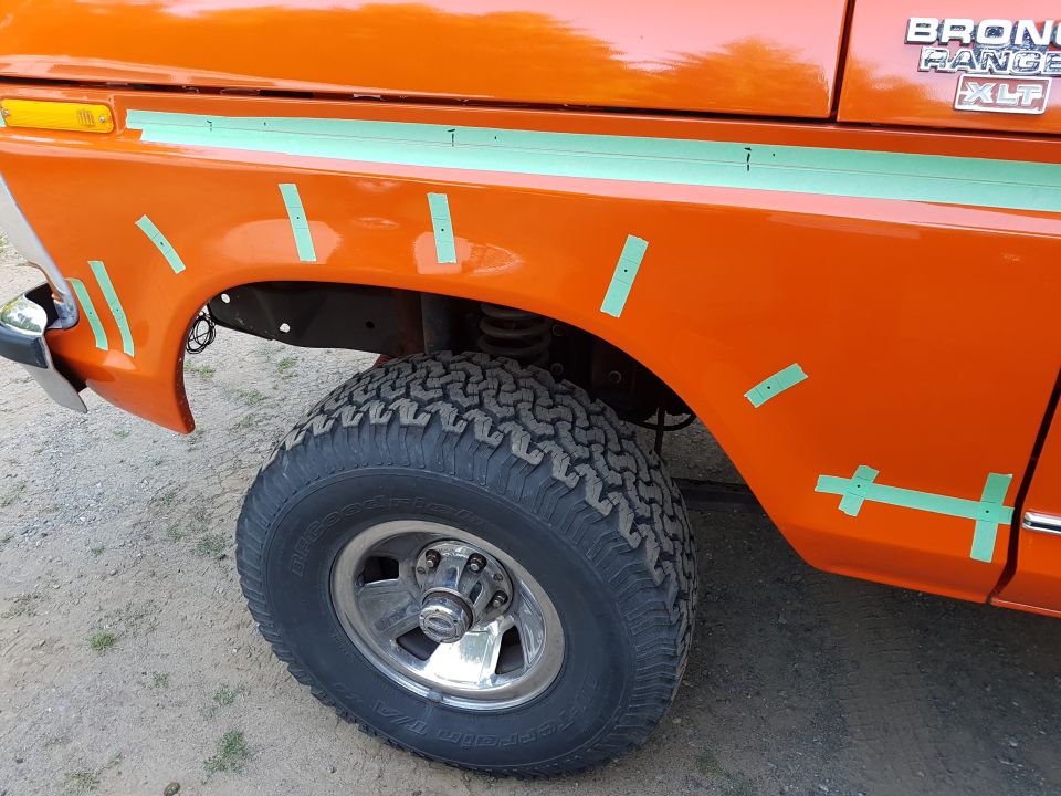 Orange 1978 Ford Bronco right front fender with green tape grid and tire.