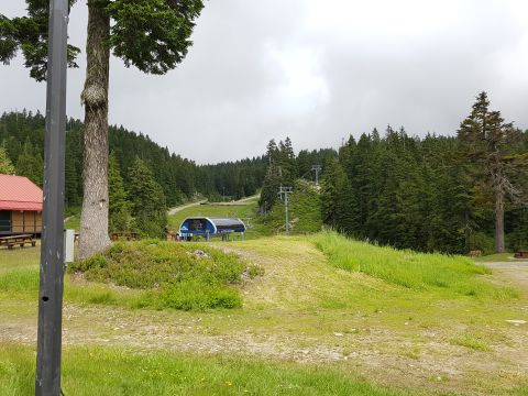 1978 Ford Bronco - A ski lift station is visible in a mountainous, forested area with a cloudy sky.