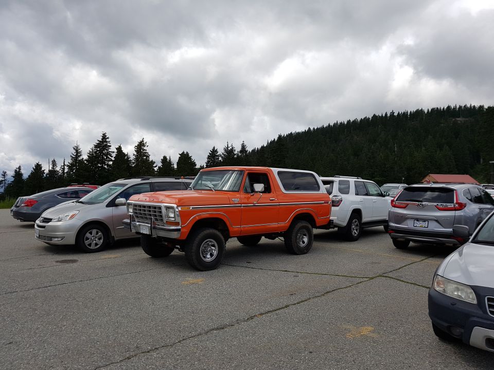 Orange SUV parked in a lot with other vehicles under a cloudy sky