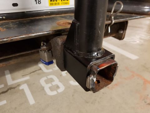 1978 Ford Bronco - A close-up view of a trailer hitch receiver and padlock, with parking space markings visible on the concrete floor.