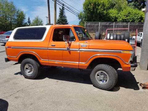 1978 Ford Bronco - This orange Ford Bronco, believed to be a 1978 model, is parked outdoors with a white hardtop.