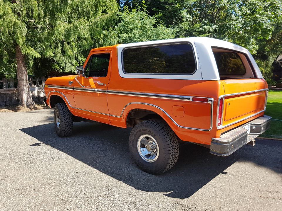 Orange and white 1978 Ford Bronco, rear quarter view, parked on asphalt