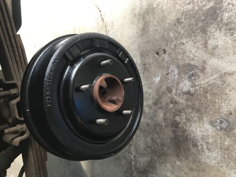 1996 Ford Bronco - Newly painted brake drum assembly with visible part numbers and attached to vehicle suspension components.