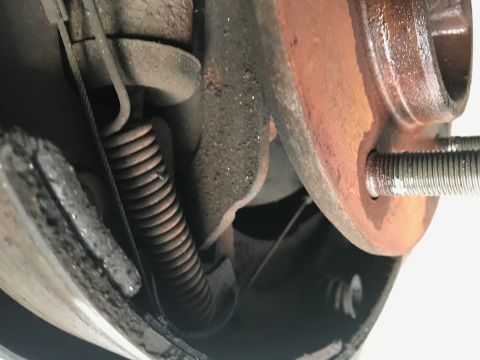 1996 Ford Bronco - A close-up view of a vehicle's brake drum and spring assembly, showing signs of rust and wear.