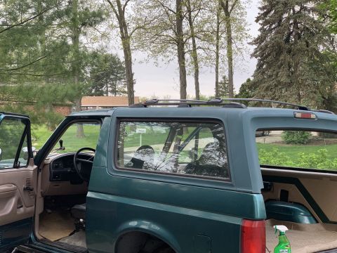 1996 Ford Bronco - Side view of a green Ford Bronco with doors open, showing the interior and roof rack.