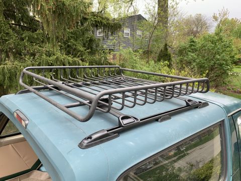 1996 Ford Bronco - The roof of a blue SUV is fitted with a black cargo rack, with the interior partially visible through the window.
