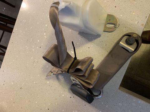1996 Ford Bronco - A vehicle seatbelt assembly is shown, with the webbing neatly bundled.