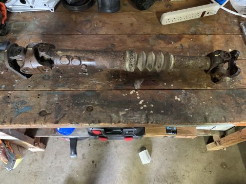 1996 Ford Bronco - A driveshaft is shown on a workbench, with various tools and parts in the background.