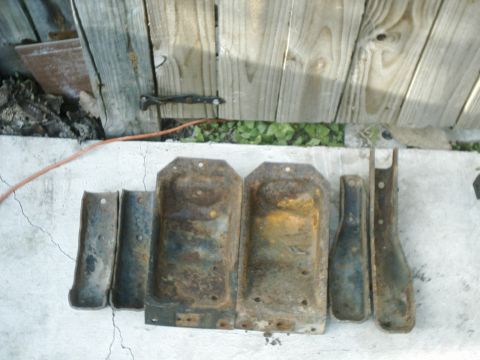 1984 Ford Bronco - Collection of old, rusted metal parts, possibly for a vehicle, displayed outdoors.