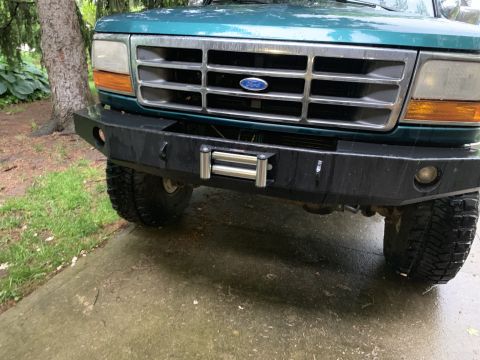 1996 Ford Bronco - Front view of a green Ford Bronco with an aftermarket bumper and winch.