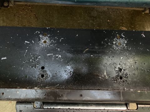 1996 Ford Bronco - This part of the vehicle frame shows damage with chipped paint and multiple holes.
