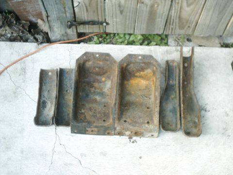 1984 Ford Bronco - A collection of aged, corroded metal components are displayed outdoors.