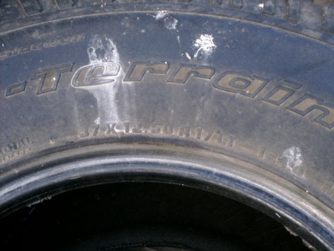 1984 Ford Bronco - Close-up of a BFGoodrich All-Terrain T/A tire, showing its size and some white markings.