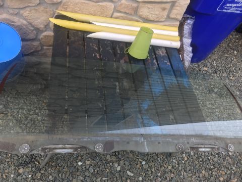 1994 Ford Bronco - Rear window assembly removed from a vehicle, resting on a wooden surface.