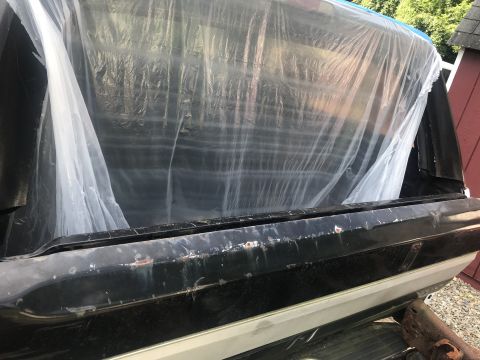 1994 Ford Bronco - The rear of a vehicle is covered with a plastic tarp, obscuring most of the interior and cargo area.