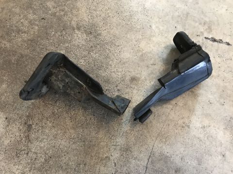 1994 Ford Bronco - Two damaged automotive components lie on a textured concrete surface.