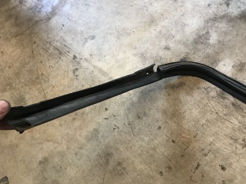 1994 Ford Bronco - A damaged rubber seal lies on a concrete surface, showing a clear break in its structure.