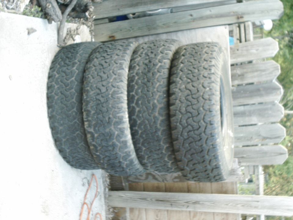 Four off-road tires stacked on a surface