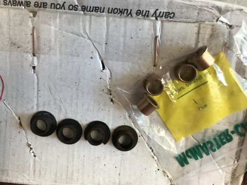 1994 Ford Bronco - Metal bushings and washers are laid out on a cardboard box, with some parts in plastic packaging.
