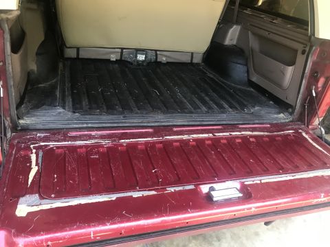 1994 Ford Bronco - The cargo area and tailgate of a red 1994 Ford Bronco are shown.