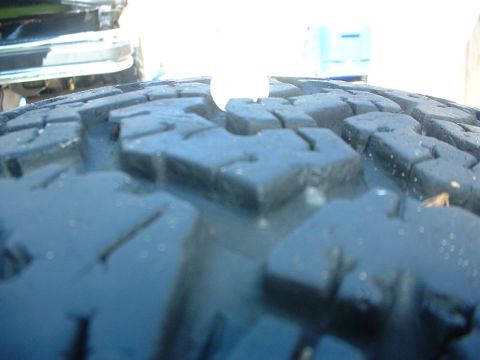 1984 Ford Bronco - Tire tread detail shot, with a white object partially covering the pattern.