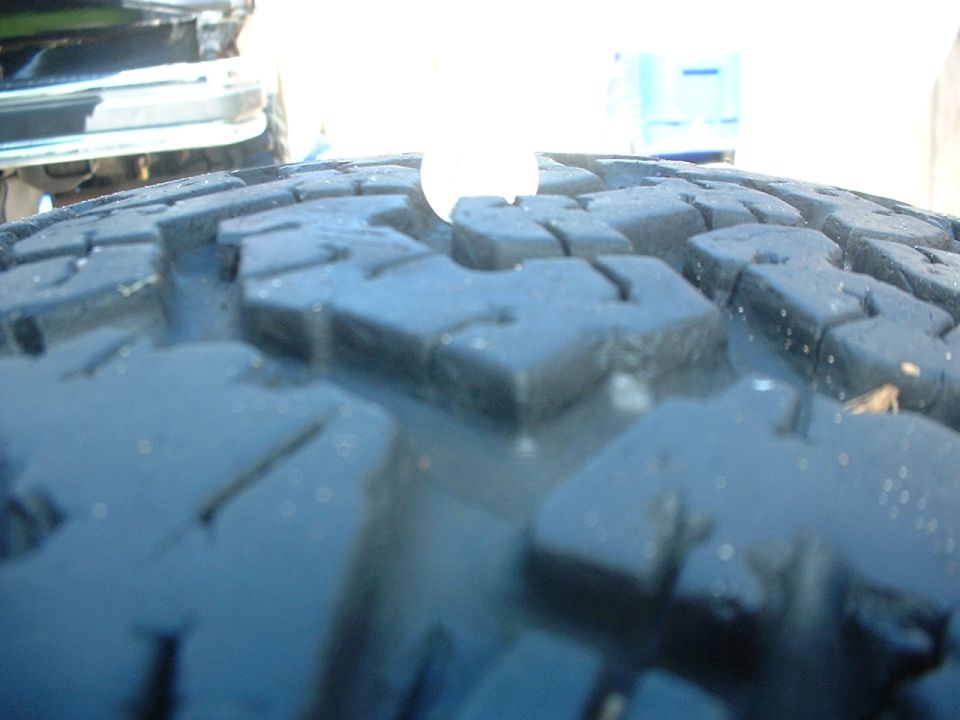 Close-up of a tire tread with a white circular object obscuring part of the pattern