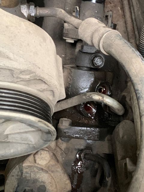 1996 Ford Bronco - Close-up view of a leaking engine component, with fluid visible around a fitting and hoses.