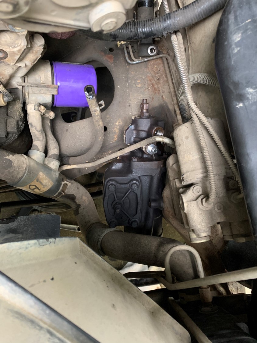 Close-up of a vehicle's steering gear box with a purple filter and hoses