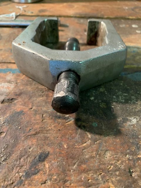 1996 Ford Bronco - A metal ball joint separator tool rests on a wooden workbench surface.